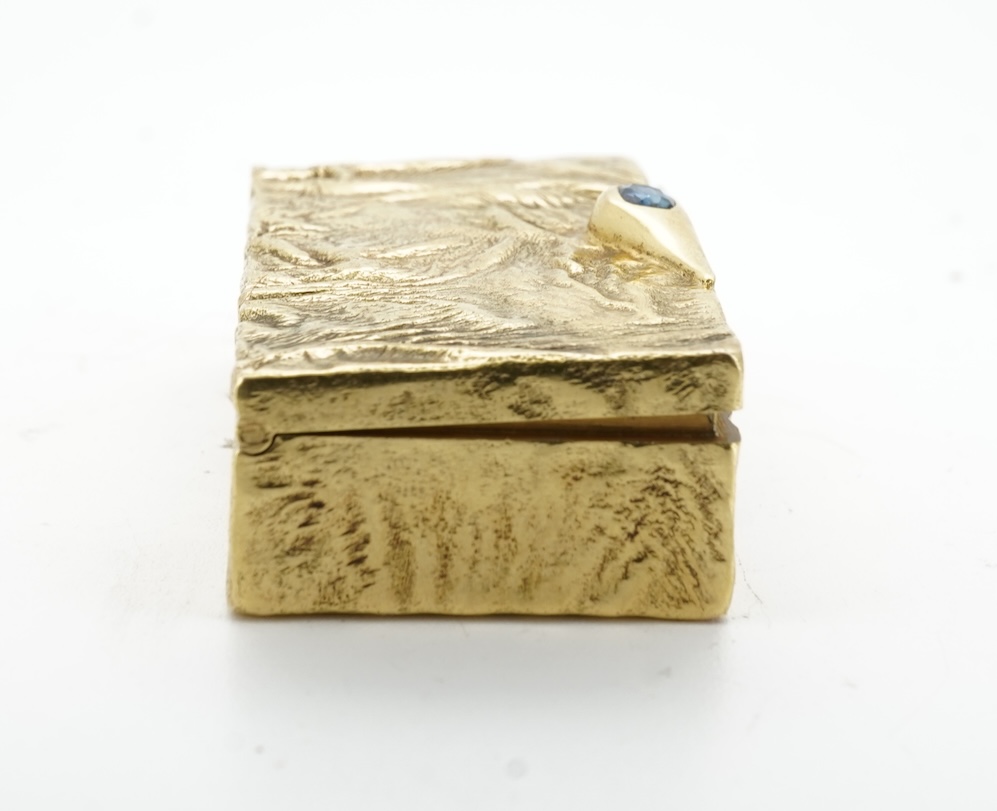 Dunhill, an attractive 9ct gold and sapphire snuffbox, circa 1973, the rectangular box of samorodok finish, the hinged lid set with a foil-backed oval sapphire, measuring approximately 5.1 x 2.7 x 1.6cm, signed Dunhill L